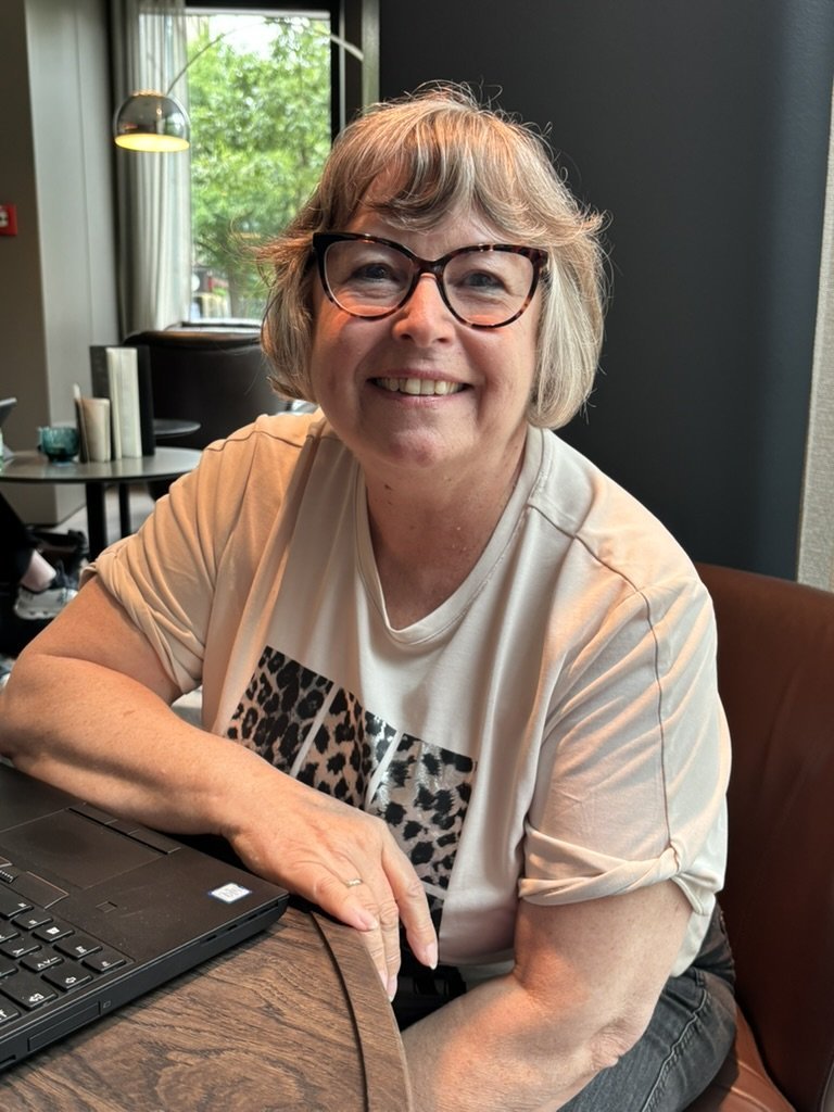 Manuela Bletzer sitzt lächelnd am Laptop und arbeitet am Newsletter einer Kundin
